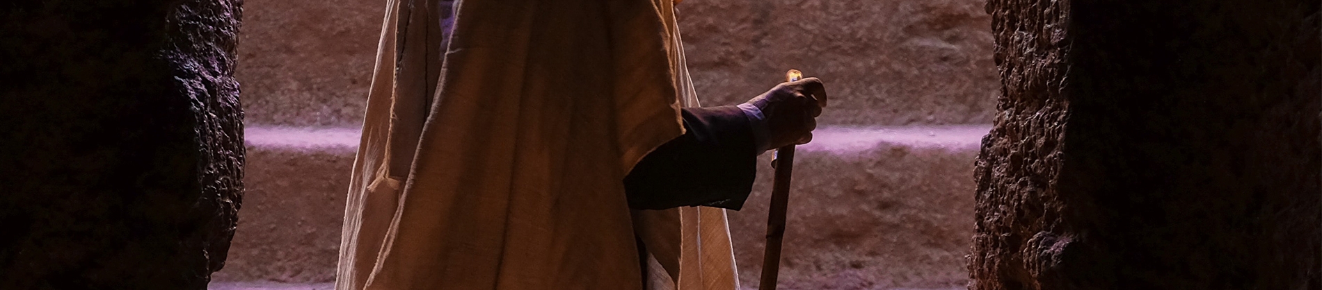 A man stood with a staff at the entrance to a cave A man stood with a staff at the entrance to a cave