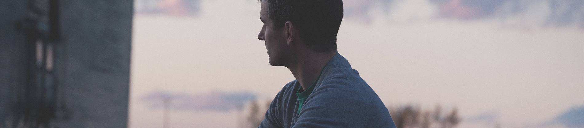 A man looking out over a purple sunset sky A man looking out over a purple sunset sky