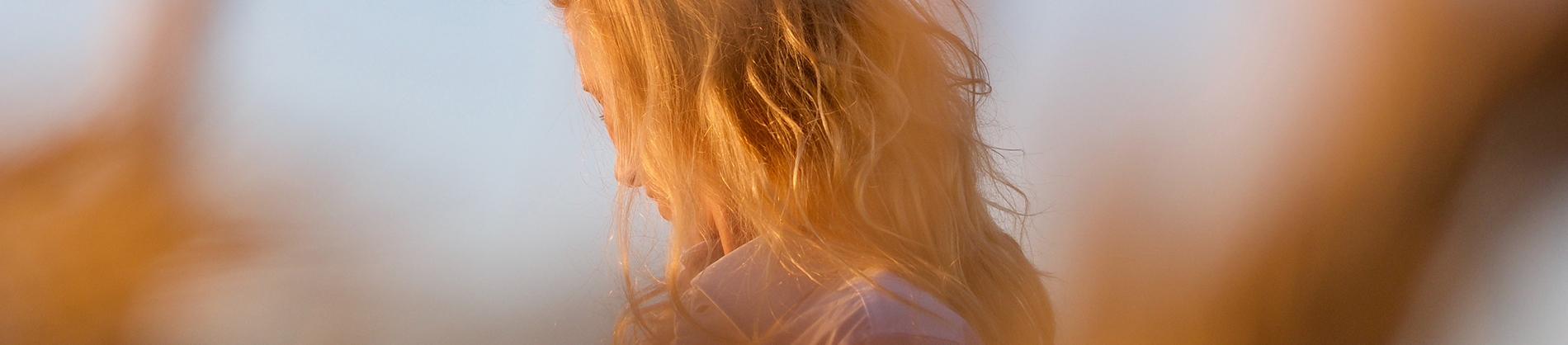 A women looking down with the sun shining on her A women looking down with the sun shining on her