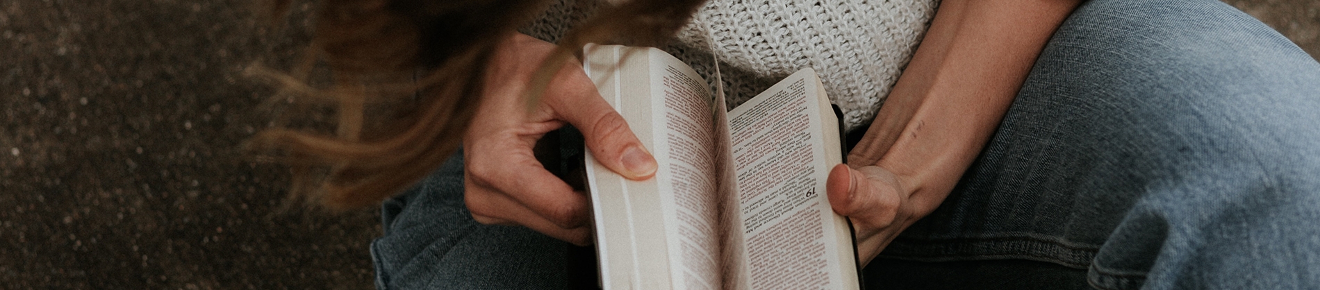 A women sat on the ground looking through her bible A women sat on the ground looking through her bible