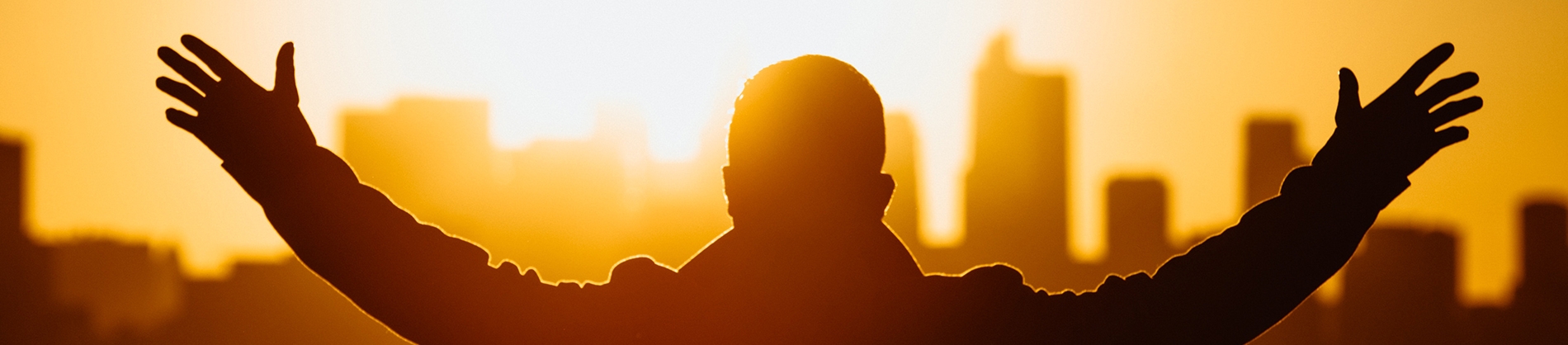 A man with his hands in the air facing a sunset A man with his hands in the air facing a sunset