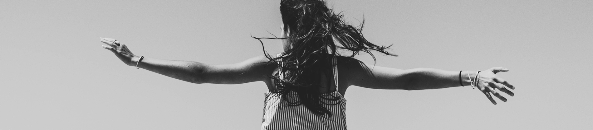 A black and white photo of a women dancing with her arms out wide A black and white photo of a women dancing with her arms out wide