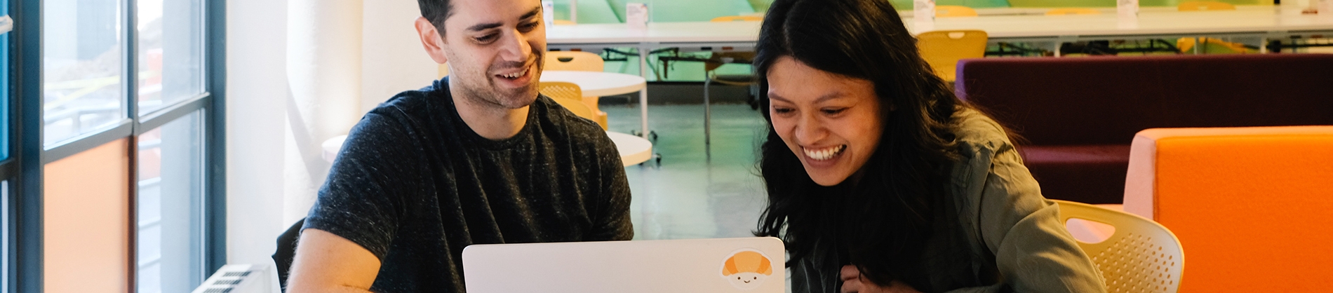 Two smiling colleagues working on a laptop together Two smiling colleagues working on a laptop together