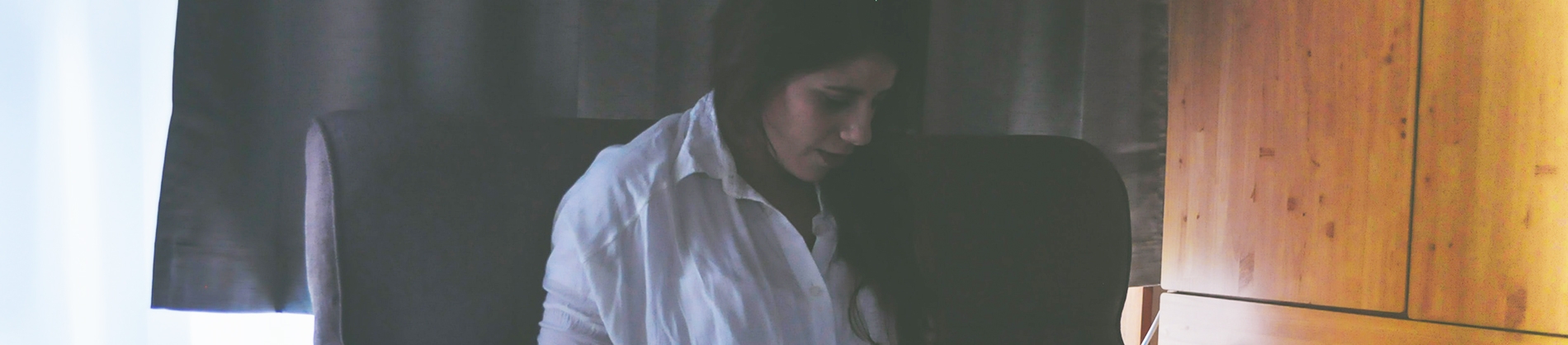 A women sat on an armchair looking down at her lap A women sat on an armchair looking down at her lap