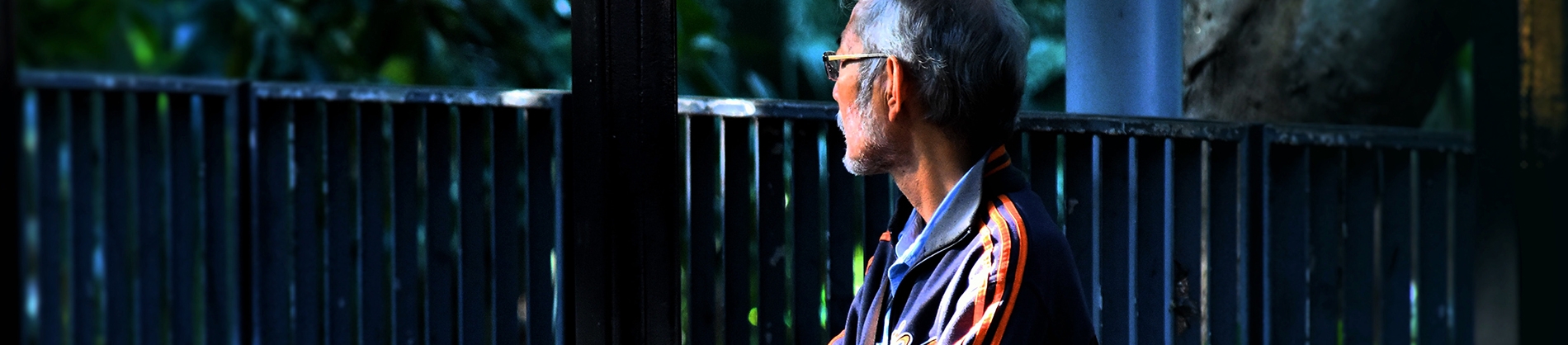 A man sat by some railings looking off into the distance A man sat by some railings looking off into the distance