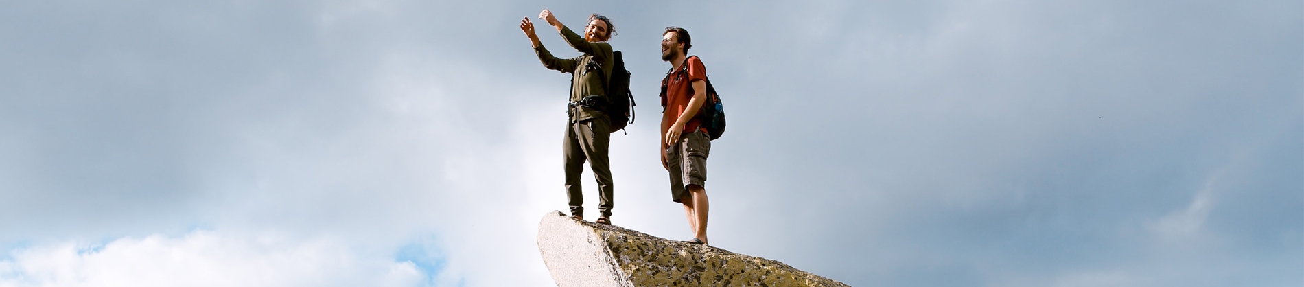 Two guys stood on top of a rock pointing and looking out Two guys stood on top of a rock pointing and looking out