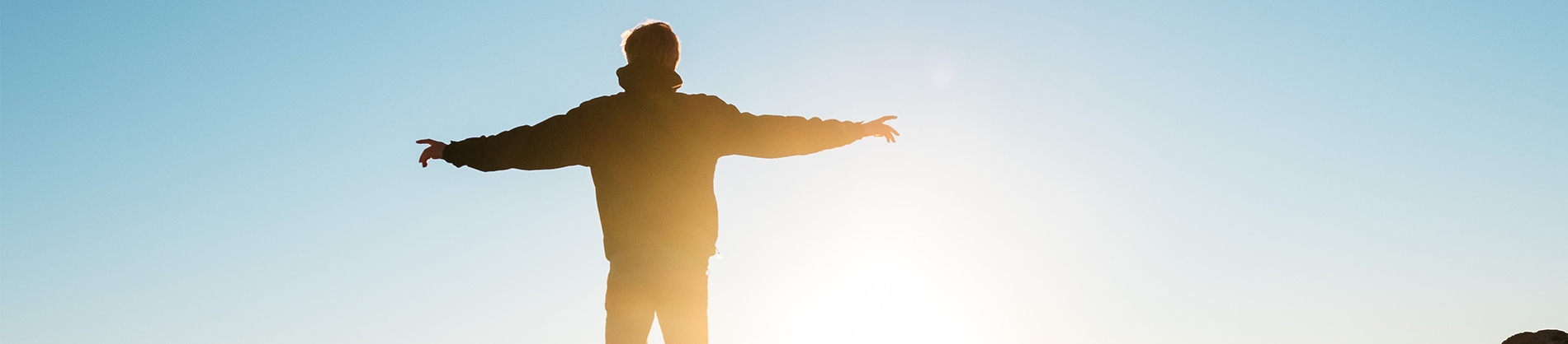 A man stood with his arms wide open and the sun shining on him A man stood with his arms wide open and the sun shining on him