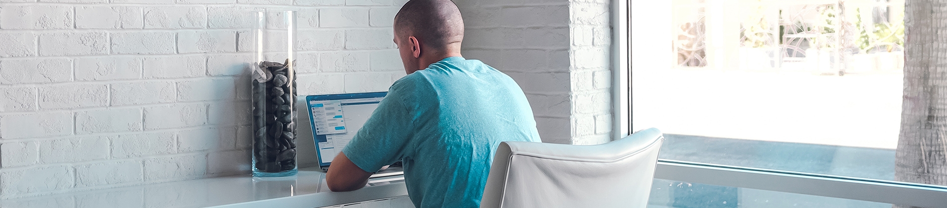A man sat at a white desk on his laptop A man sat at a white desk on his laptop