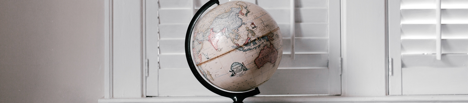 A globe sat on a shelf with white shutters behind A globe sat on a shelf with white shutters behind