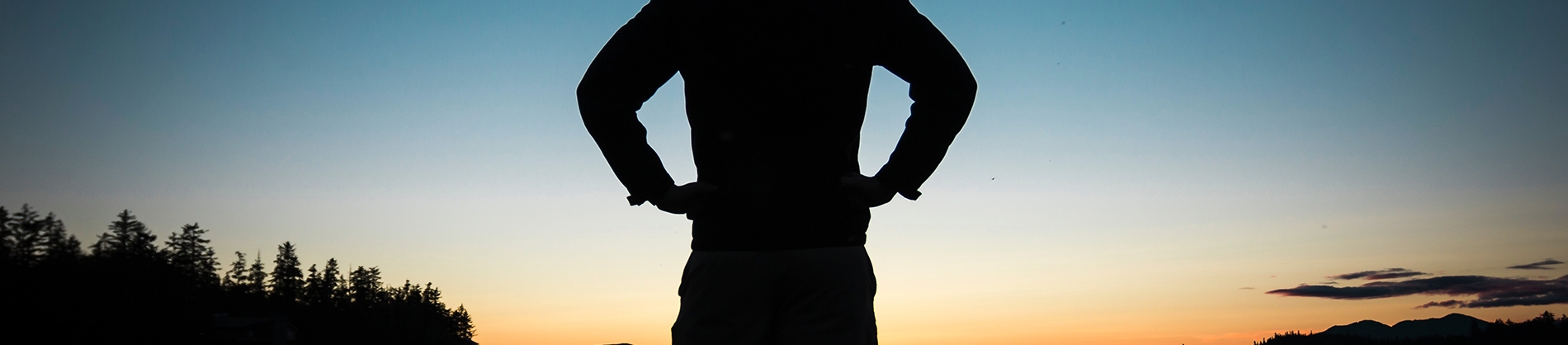 A silhouette of a man stood in front of a sunrise A silhouette of a man stood in front of a sunrise