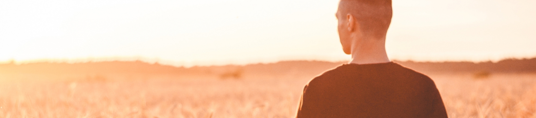 A guy stood in a field with the sun shining on him A guy stood in a field with the sun shining on him
