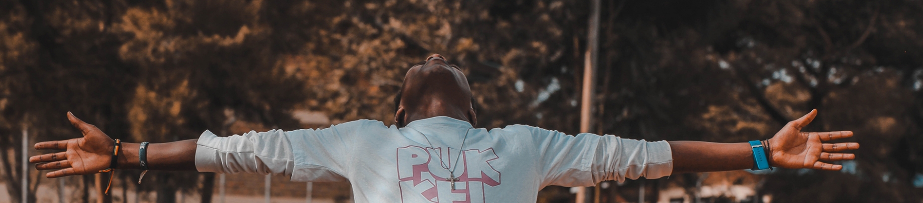 A man in a park with his arms stretched out wide and face towards the sky A man in a park with his arms stretched out wide and face towards the sky