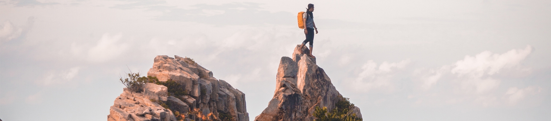 A person stood on a rock with the clouds behind them A person stood on a rock with the clouds behind them