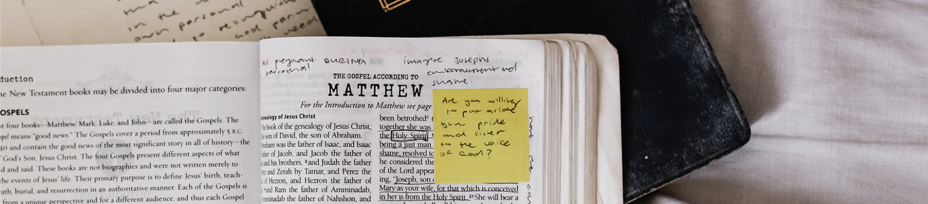 Open bible with notes and post-it note stuck on the page Open bible with notes and post-it note stuck on the page