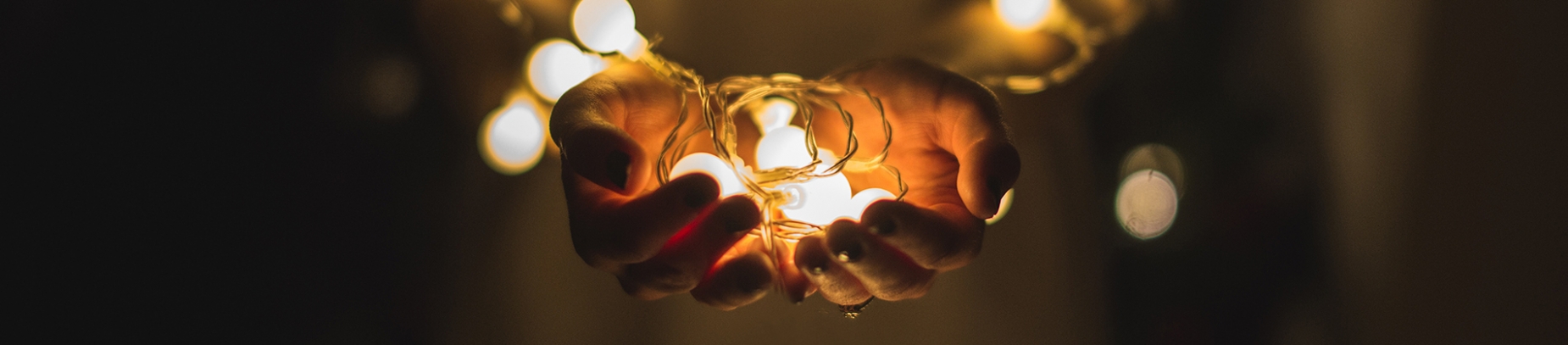 A women holding lit string light bulbs A women holding lit string light bulbs