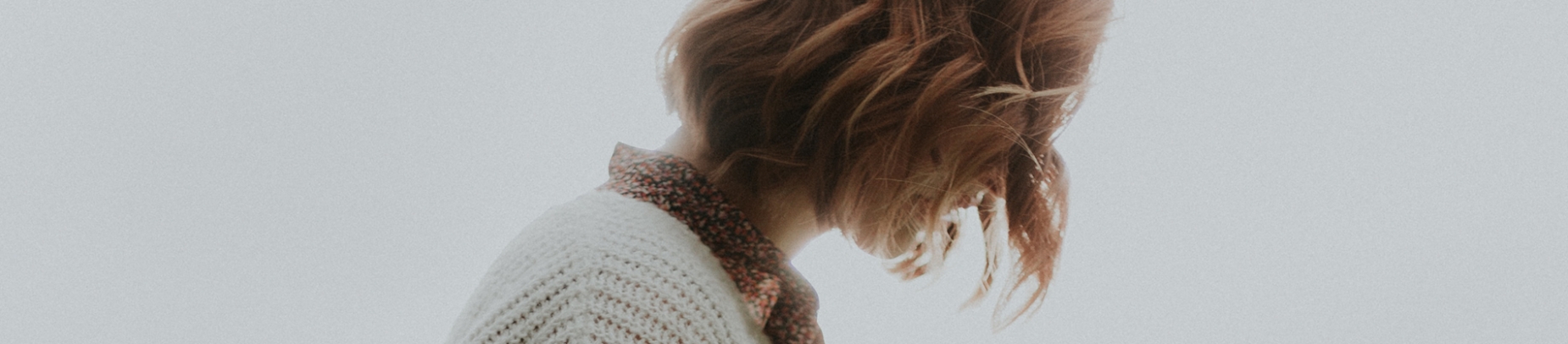 A side profile of a woman looking down with her hair falling over her face A side profile of a woman looking down with her hair falling over her face