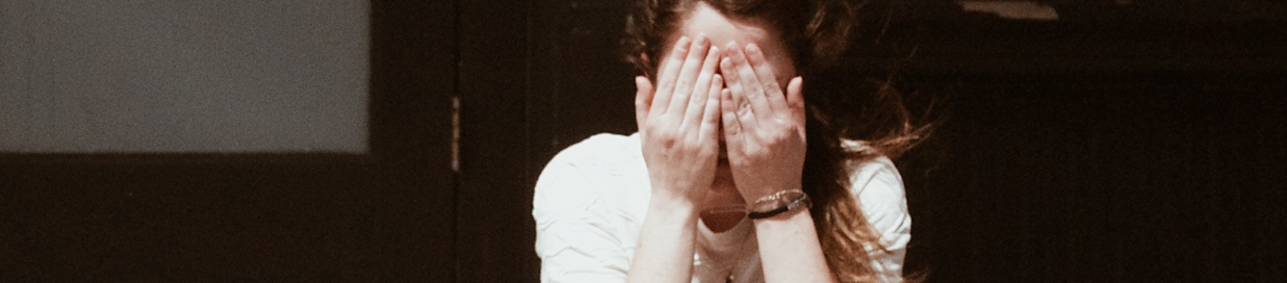A women with her hands over her face A women with her hands over her face