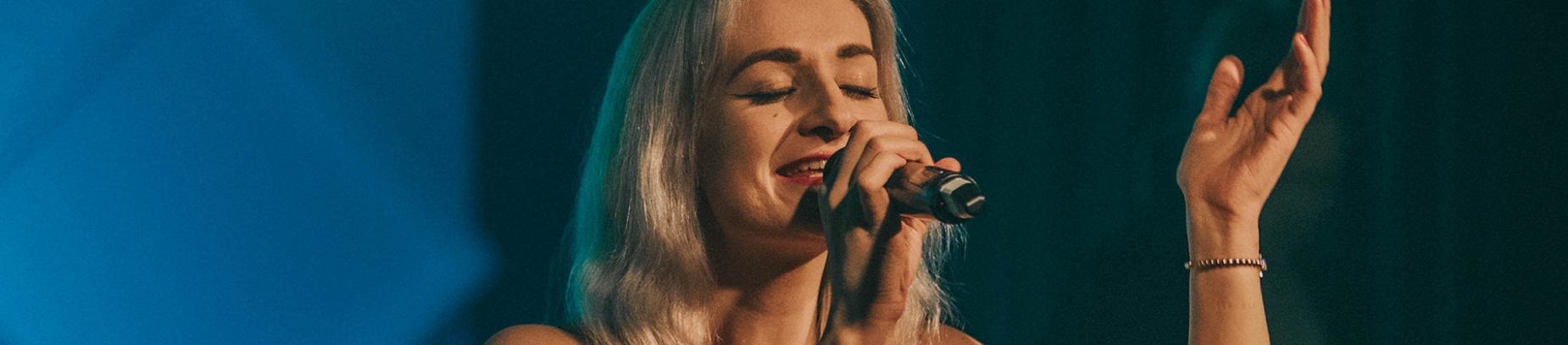 A woman leading worship with her hand in the air A woman leading worship with her hand in the air