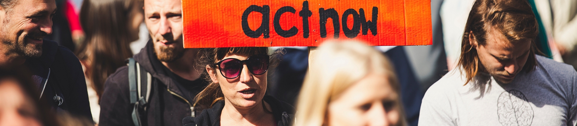 Group of people protesting with 'act now' sign Group of people protesting with 'act now' sign