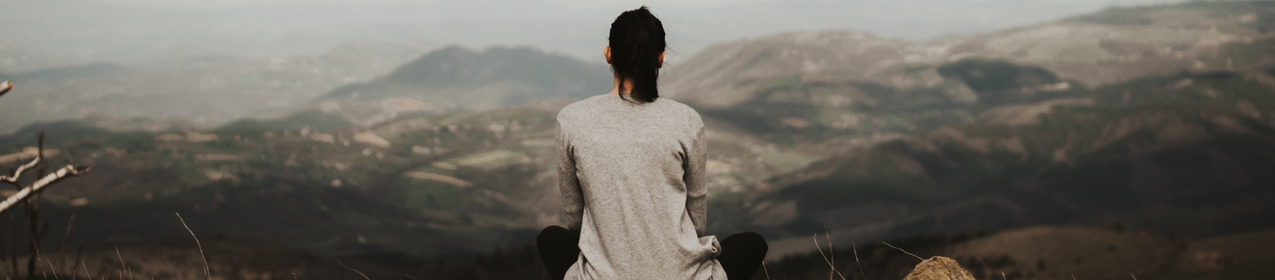 A women sat looking out over a mountain landscape A women sat looking out over a mountain landscape