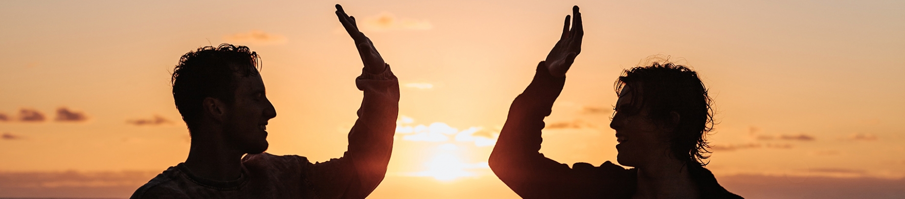 Two men high fiving each other with the sunset behind them Two men high fiving each other with the sunset behind them