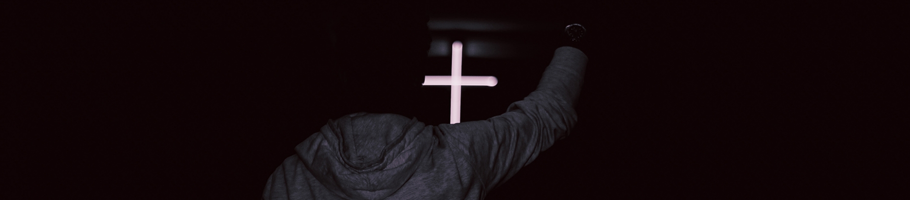 A guy with his arm up in praise in front of a glowing cross A guy with his arm up in praise in front of a glowing cross