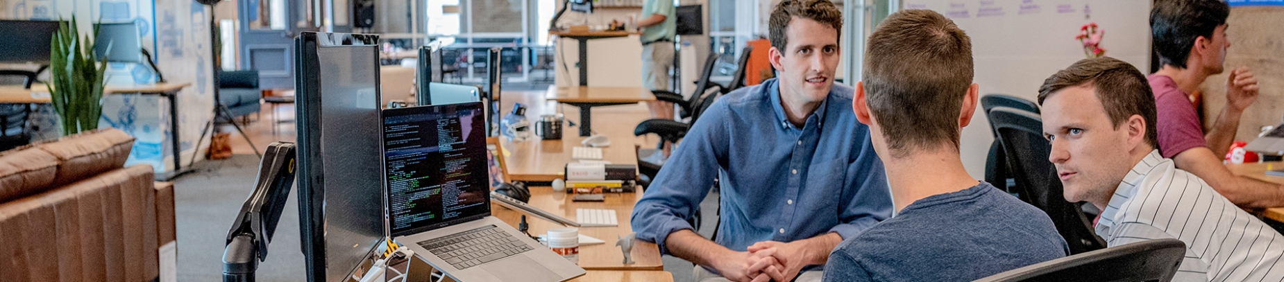 Three guys sat at a office desk talking Three guys sat at a office desk talking