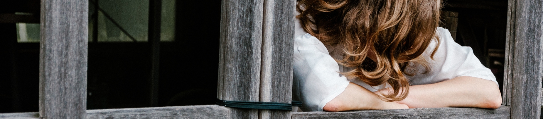 A women leaning on a wooden ledge with her head down A women leaning on a wooden ledge with her head down