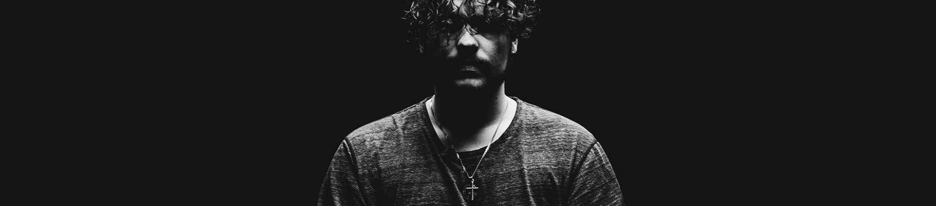 A black and white photo of a guy wearing a cross necklace looking hopeless A black and white photo of a guy wearing a cross necklace looking hopeless