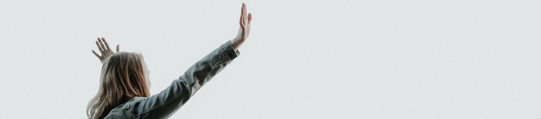 A women in a denim jacket with her arms up in the air A women in a denim jacket with her arms up in the air