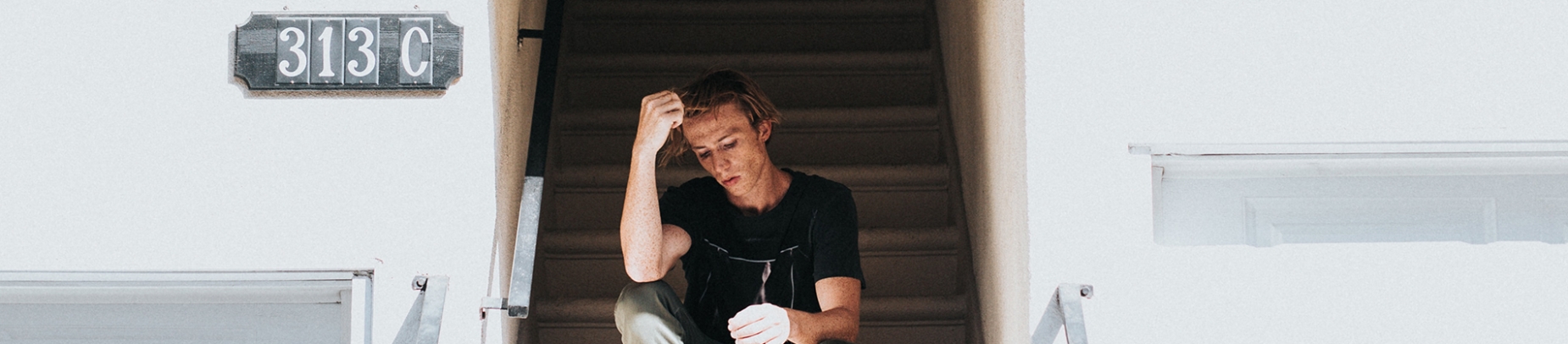 A man sat on some steps with his hand up to his head A man sat on some steps with his hand up to his head