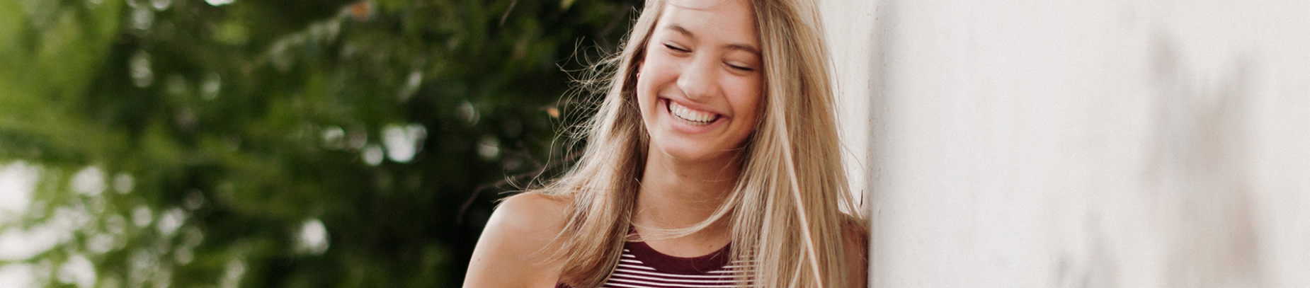 A girl smiling and leaning against a white wall A girl smiling and leaning against a white wall