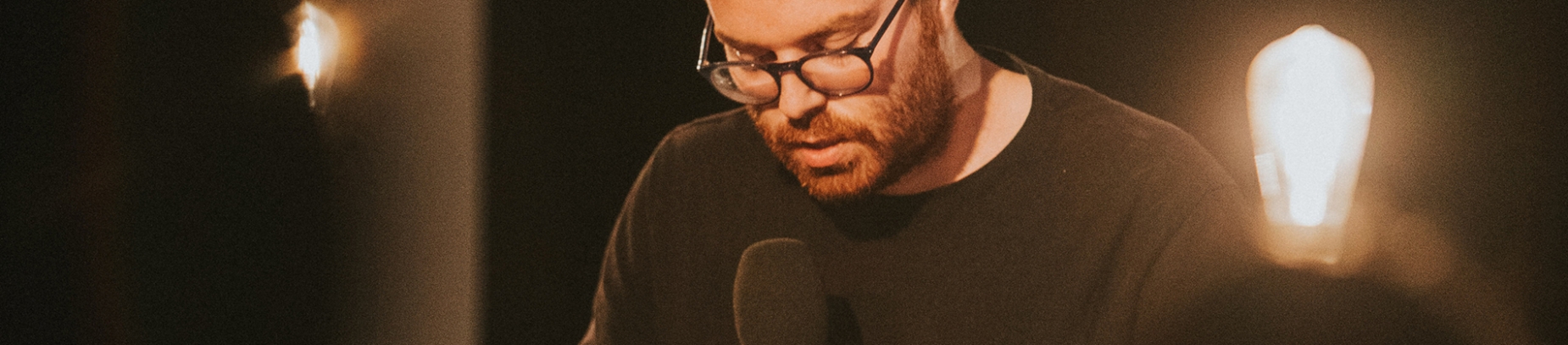A man talking into a microphone with bulb lights surrounding him A man talking into a microphone with bulb lights surrounding him