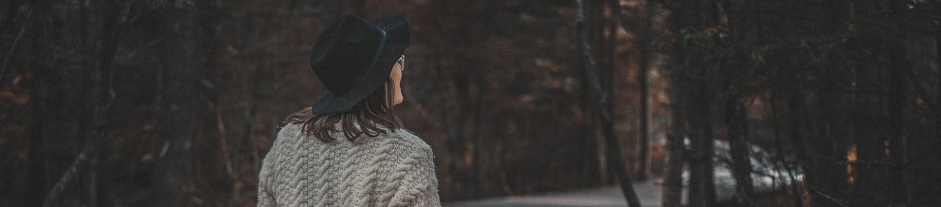 A women walking down a road towards a forest A women walking down a road towards a forest