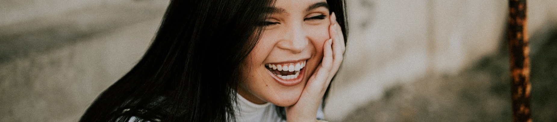 A women laughing with her hand on her cheek A women laughing with her hand on her cheek