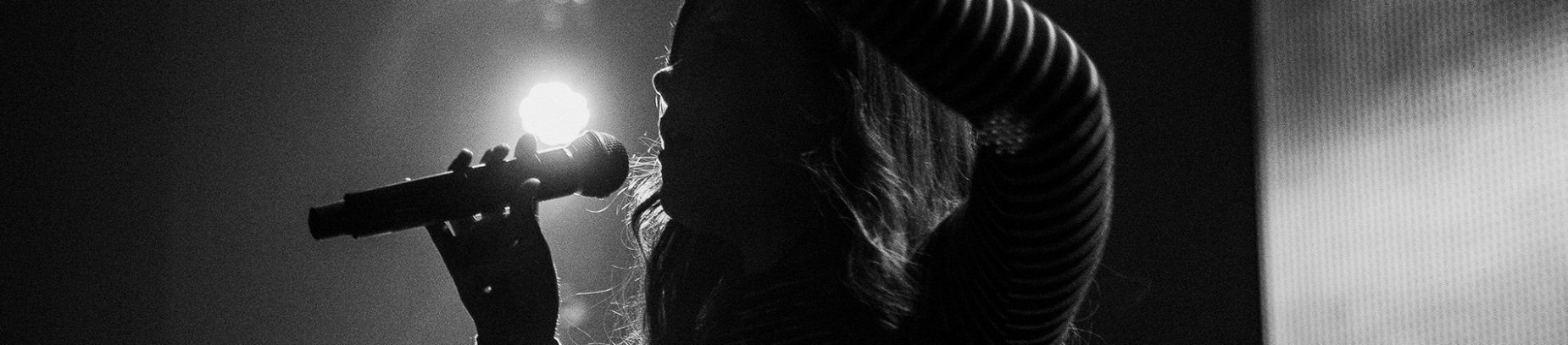 A woman leading worship with her hand in the air holding a microphone A woman leading worship with her hand in the air holding a microphone