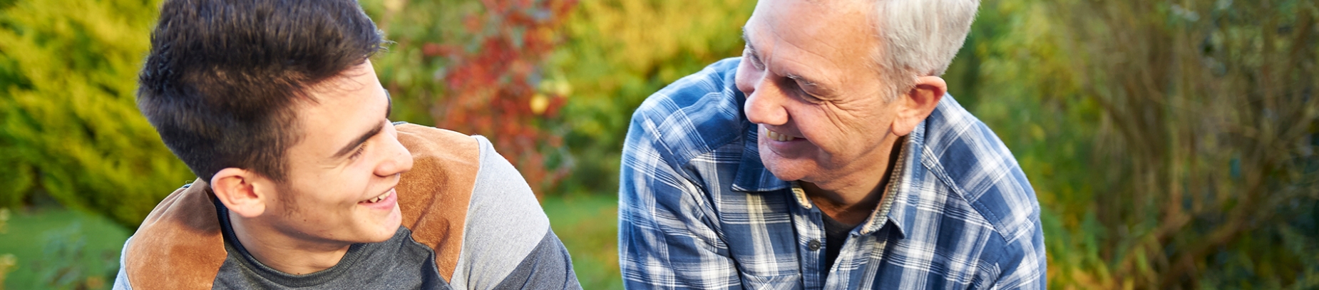 A father and son sat in the garden, smiling at each other A father and son sat in the garden, smiling at each other