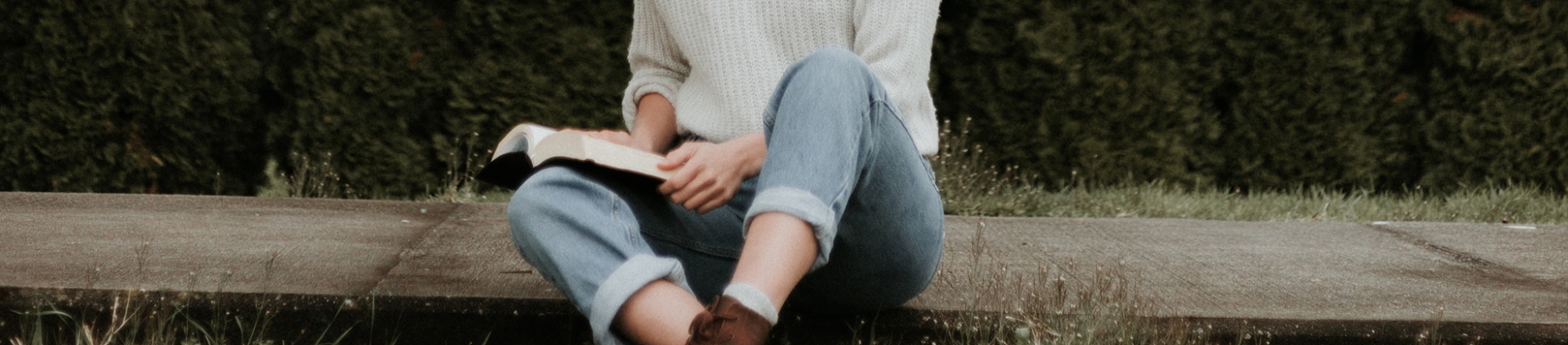 A women sat on the pavement reading the bible A women sat on the pavement reading the bible