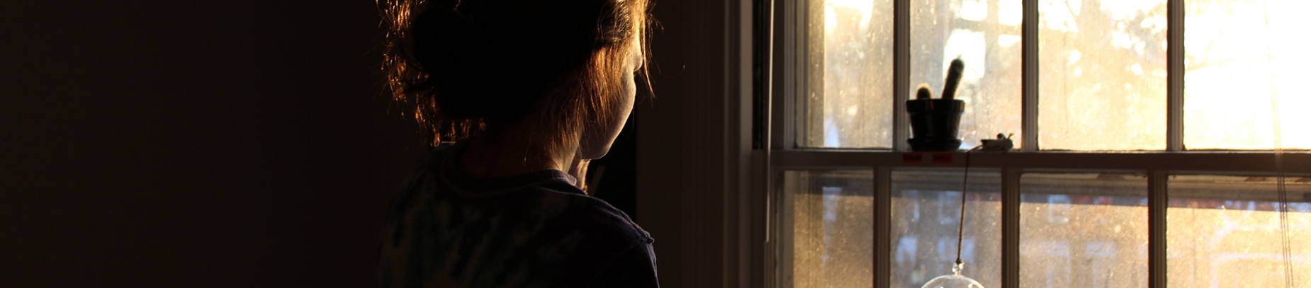 A women looking out of a window towards the light A women looking out of a window towards the light