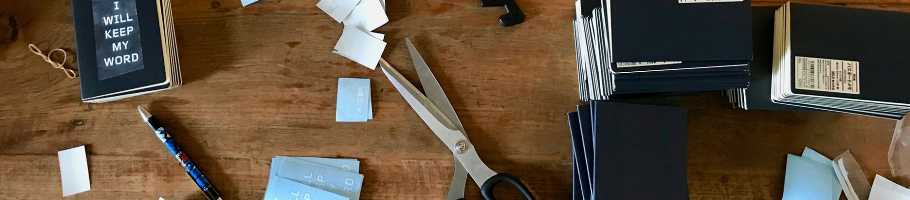 A desk covered in notebooks, scissors and cut up paper A desk covered in notebooks, scissors and cut up paper