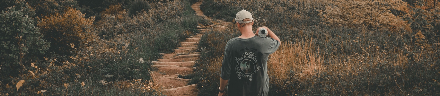 A guy walking down a steps with grass and bushes either side A guy walking down a steps with grass and bushes either side