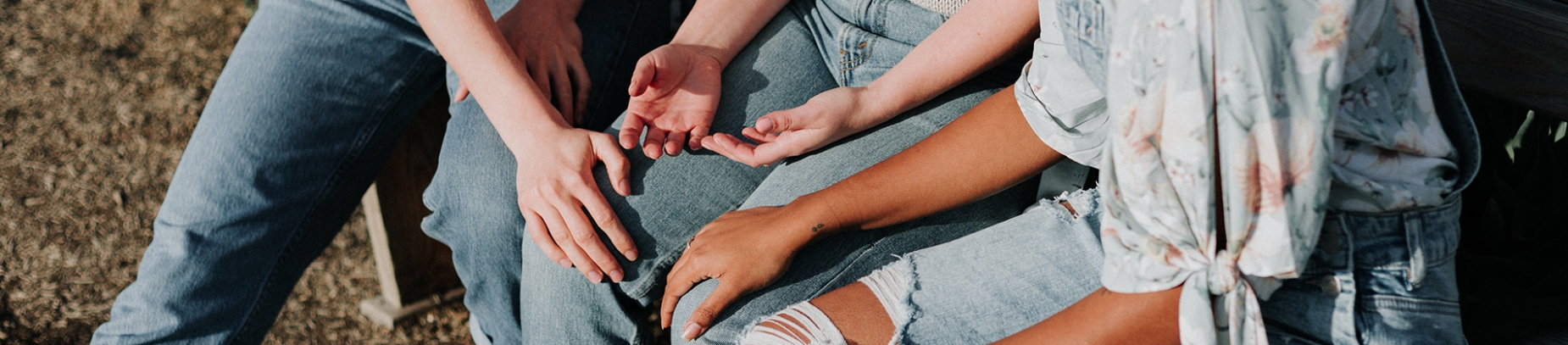 Two women praying for their friend with their hands rested on her knee Two women praying for their friend with their hands rested on her knee