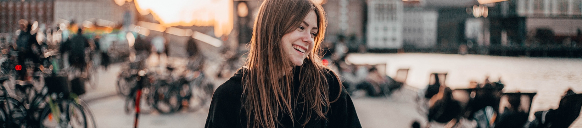 A woman looking sidewards and smiling with a busy street behind her A woman looking sidewards and smiling with a busy street behind her
